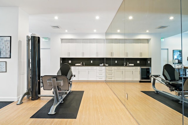 workout room featuring wine cooler, sink, and light wood-type flooring