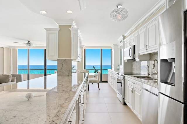 kitchen featuring a water view, white cabinetry, stainless steel appliances, and light stone countertops