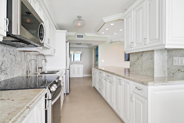 kitchen with sink, crown molding, appliances with stainless steel finishes, white cabinetry, and light stone countertops