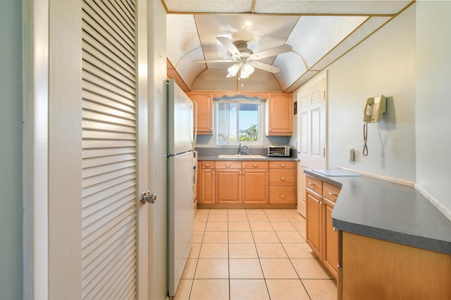 kitchen with light tile patterned flooring, refrigerator, lofted ceiling, sink, and ceiling fan