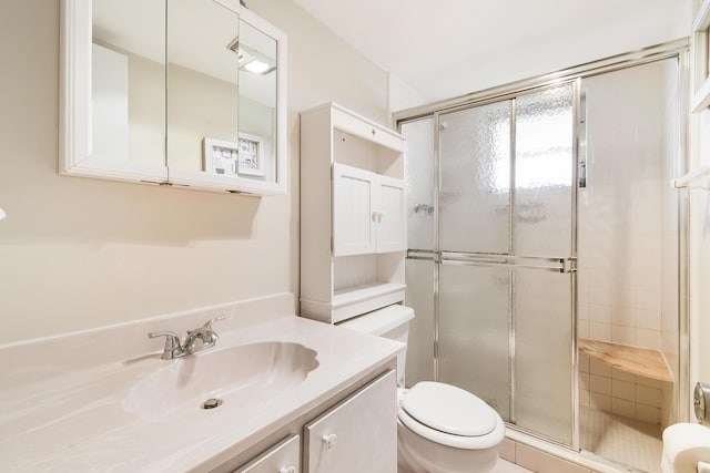 bathroom with vanity, toilet, and a shower with door