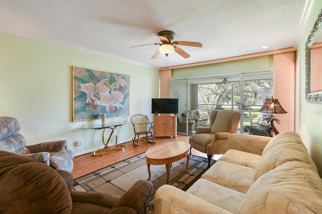 living room featuring wood finished floors, a textured ceiling, ceiling fan, baseboards, and ornamental molding