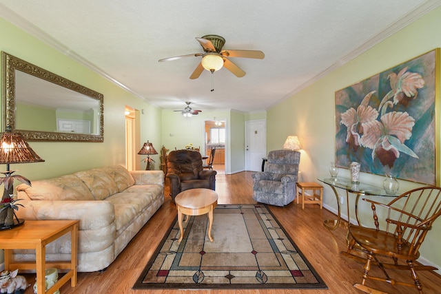 living room featuring hardwood / wood-style flooring, ceiling fan, and crown molding