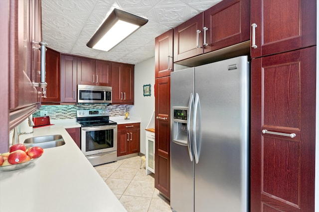 kitchen featuring stainless steel appliances, sink, light tile patterned floors, and backsplash