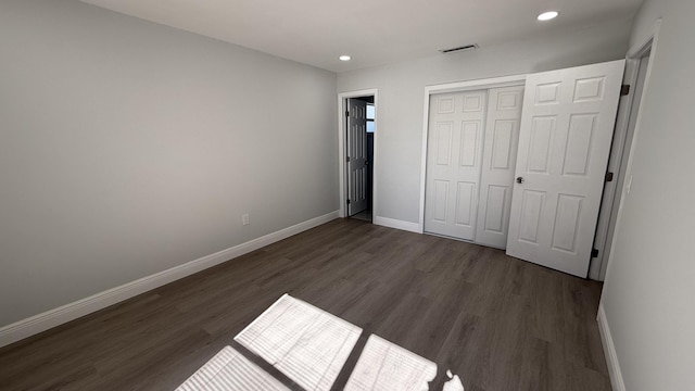 unfurnished bedroom with dark wood-type flooring and a closet