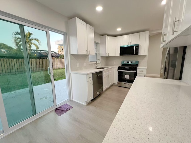 kitchen with white cabinetry, stainless steel appliances, and light wood-type flooring