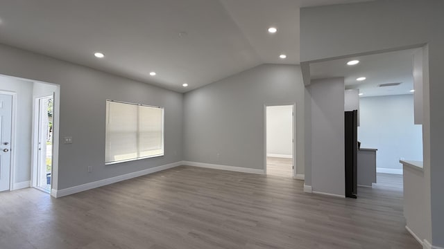 unfurnished living room with lofted ceiling, a healthy amount of sunlight, and light wood-type flooring