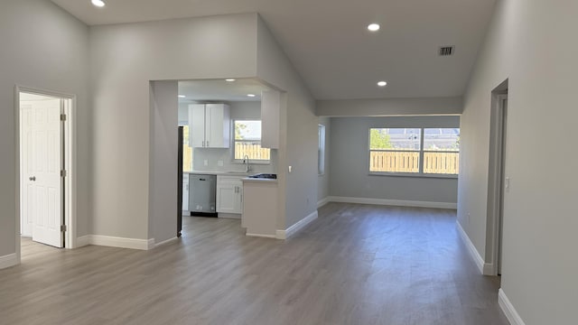 interior space featuring sink, stainless steel dishwasher, light hardwood / wood-style floors, and white cabinets