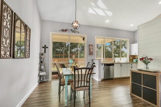 dining room with dark wood-type flooring, a healthy amount of sunlight, and a textured ceiling