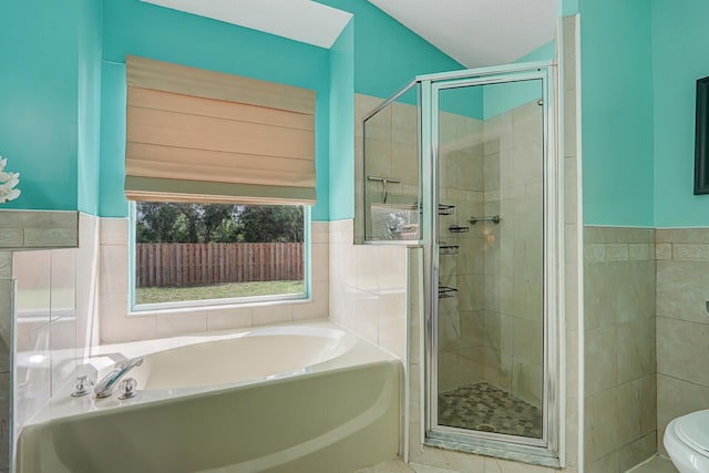 bathroom featuring tile walls, plus walk in shower, and toilet