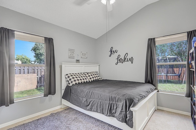 bedroom with multiple windows, vaulted ceiling, carpet flooring, and ceiling fan