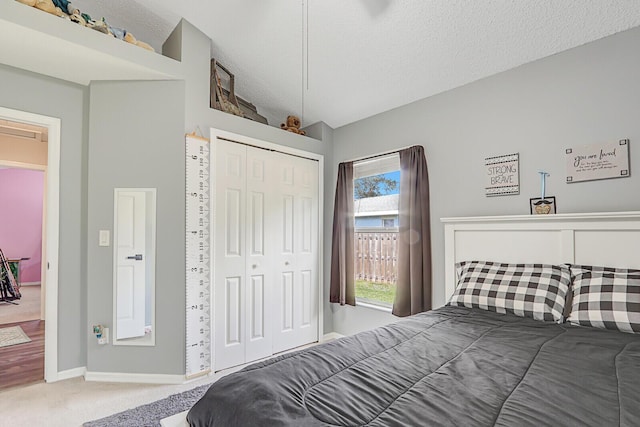 carpeted bedroom featuring vaulted ceiling, a closet, and a textured ceiling