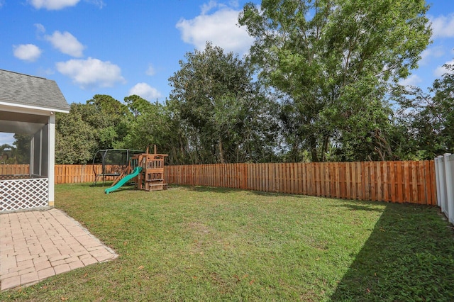 view of yard with a sunroom, a patio, and a playground