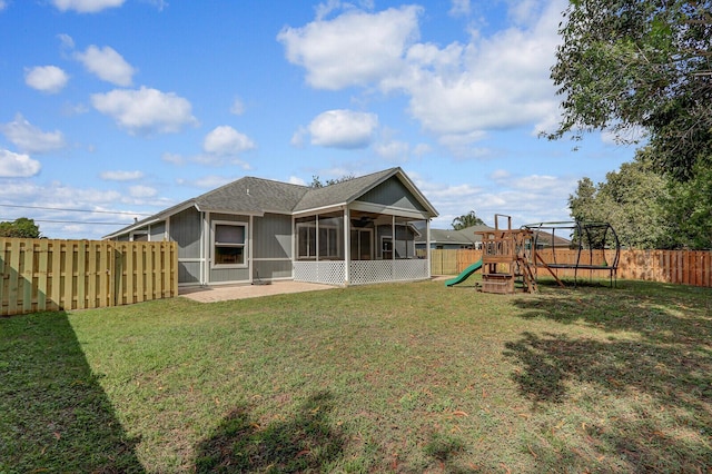 back of property with a yard, a playground, a patio area, and a sunroom