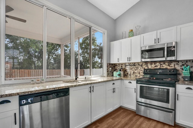 kitchen featuring sink, stainless steel appliances, wood-type flooring, white cabinets, and decorative backsplash