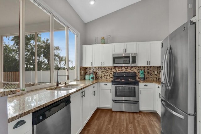 kitchen featuring sink, white cabinetry, tasteful backsplash, stainless steel appliances, and light stone countertops