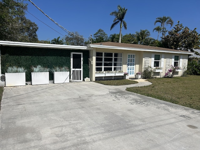 ranch-style home with stucco siding, concrete driveway, and a front yard