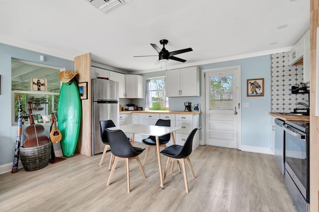 kitchen with appliances with stainless steel finishes, light hardwood / wood-style flooring, crown molding, and white cabinets