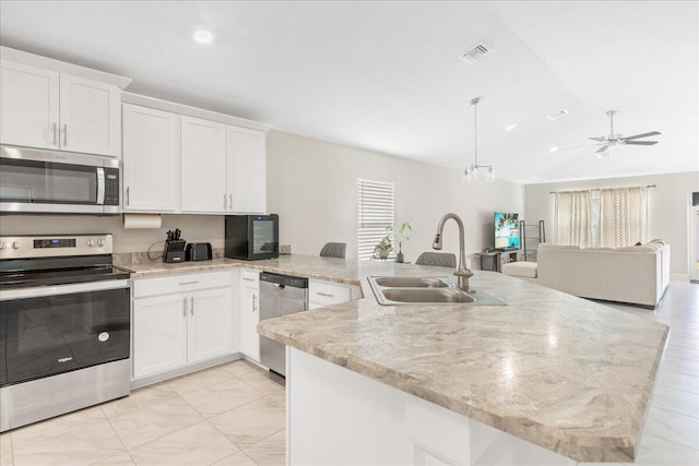 kitchen featuring white cabinetry, sink, stainless steel appliances, and hanging light fixtures