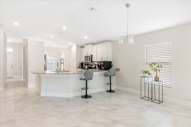 kitchen featuring pendant lighting, plenty of natural light, white cabinets, and appliances with stainless steel finishes