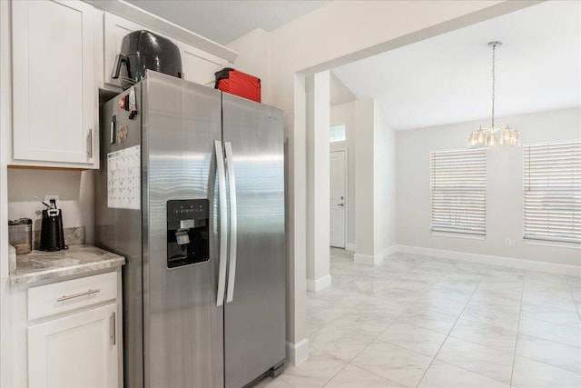 kitchen featuring stainless steel refrigerator with ice dispenser, white cabinetry, an inviting chandelier, pendant lighting, and light stone countertops