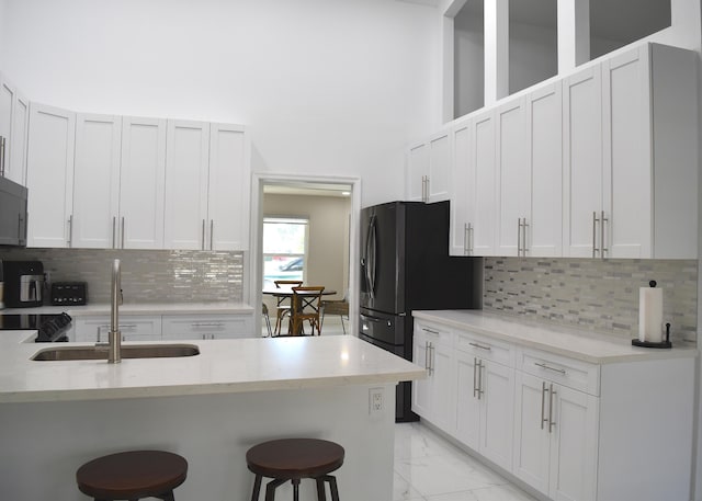 kitchen featuring white cabinetry, a breakfast bar, sink, and decorative backsplash