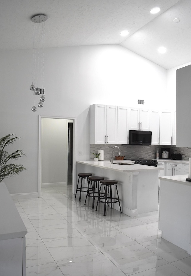 kitchen with a breakfast bar, pendant lighting, high vaulted ceiling, tasteful backsplash, and white cabinets