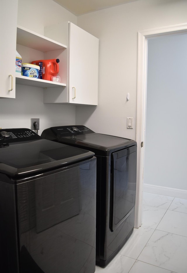 clothes washing area with cabinets and washer and clothes dryer