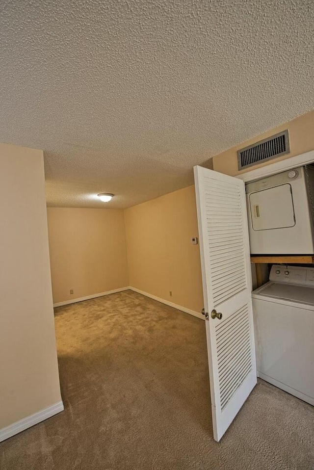 basement featuring carpet flooring, stacked washing maching and dryer, and a textured ceiling