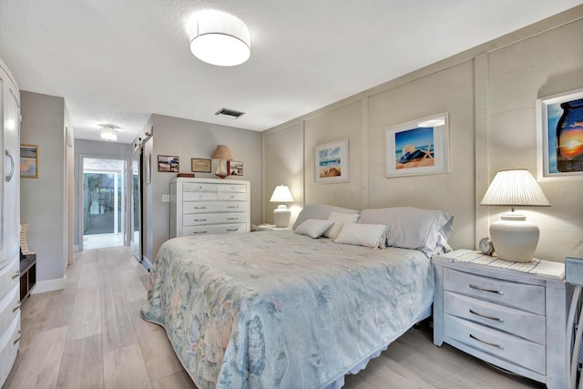 bedroom featuring a barn door and light wood-type flooring