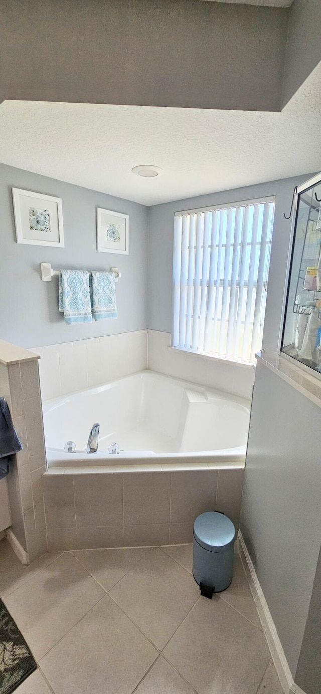 bathroom with tiled bath, tile patterned floors, and a textured ceiling