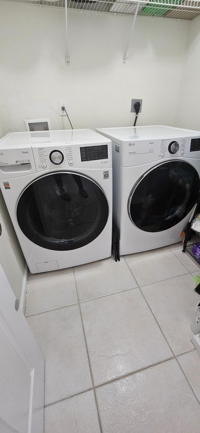 laundry room with washer and clothes dryer and tile patterned flooring