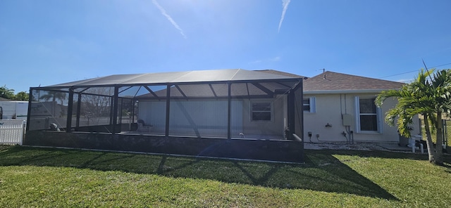 rear view of house featuring a lanai and a lawn