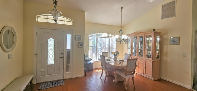 foyer entrance featuring hardwood / wood-style flooring, high vaulted ceiling, and a chandelier