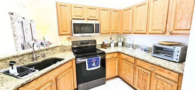 kitchen featuring stainless steel appliances, light tile patterned flooring, sink, and light stone counters