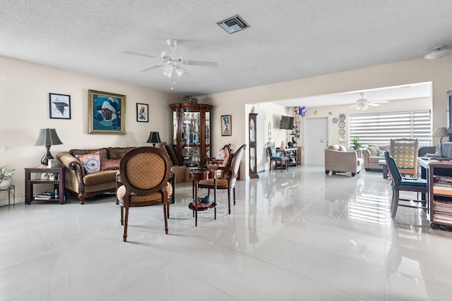 living room featuring ceiling fan, a textured ceiling, and light tile patterned floors