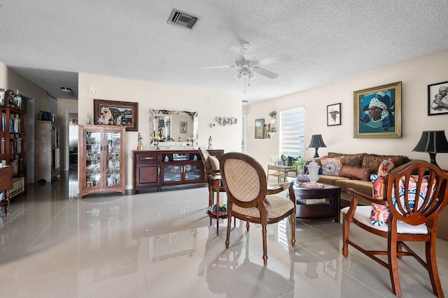 living room with light tile patterned floors, a textured ceiling, and ceiling fan