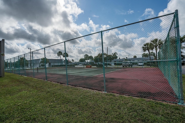 view of tennis court with a yard