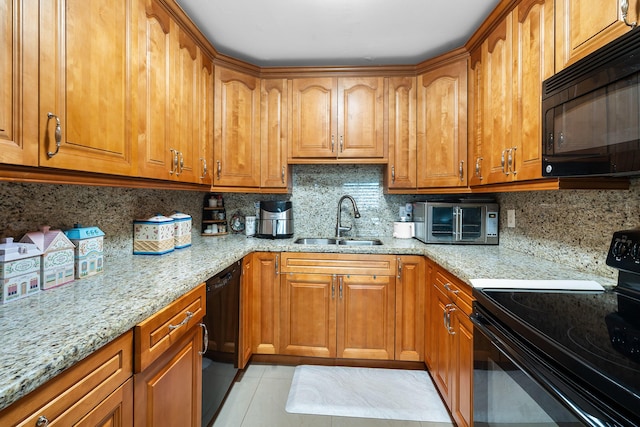 kitchen featuring tasteful backsplash, light stone countertops, sink, and black appliances