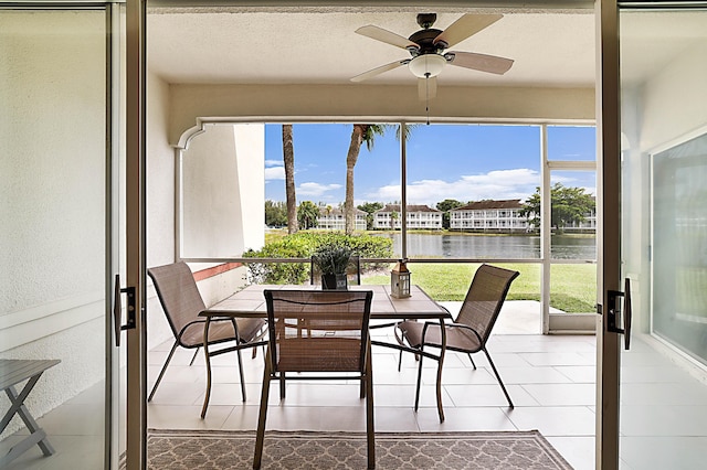 sunroom featuring a wealth of natural light, ceiling fan, and a water view