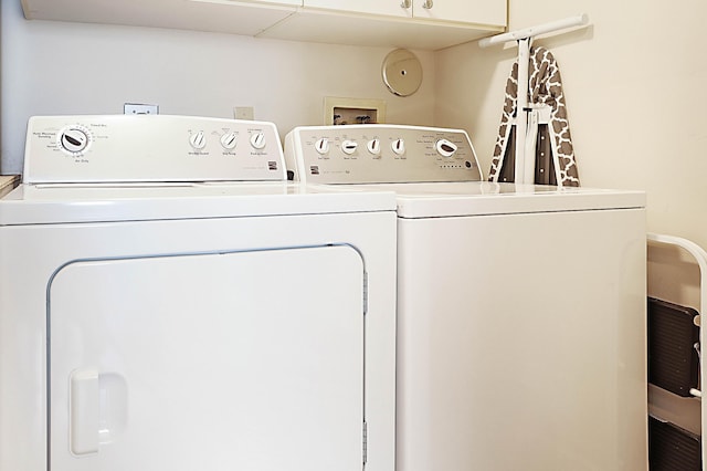 washroom featuring washing machine and dryer and cabinets