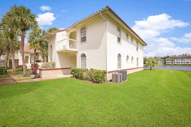 view of property exterior featuring a balcony, a lawn, and central air condition unit