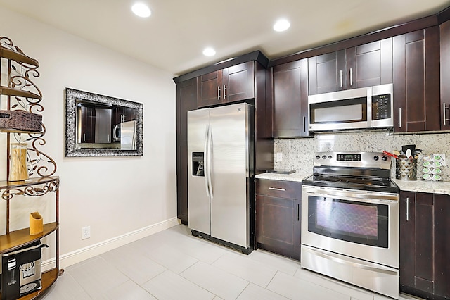 kitchen featuring backsplash, dark brown cabinets, stainless steel appliances, and light stone countertops