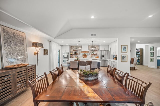 dining room with lofted ceiling, an inviting chandelier, and light hardwood / wood-style floors