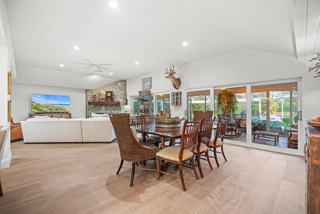 dining space featuring a stone fireplace, vaulted ceiling, and ceiling fan