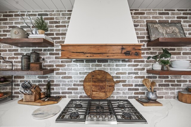 kitchen with light stone counters, stainless steel gas cooktop, and wooden ceiling