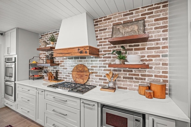 kitchen featuring light hardwood / wood-style flooring, stainless steel appliances, light stone countertops, custom exhaust hood, and wooden ceiling