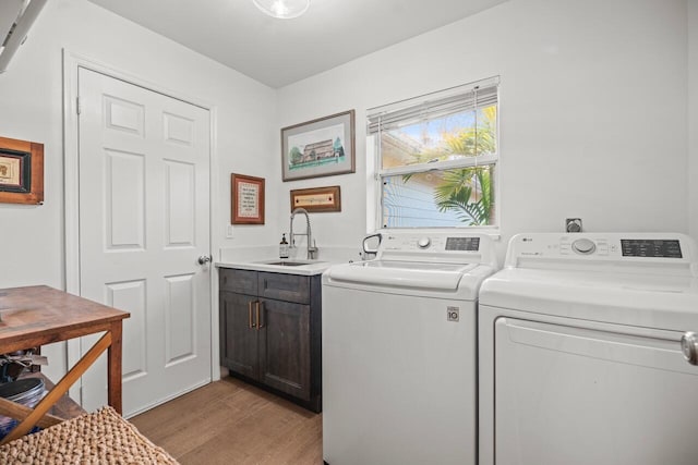 laundry room with sink, light hardwood / wood-style flooring, cabinets, and washing machine and clothes dryer