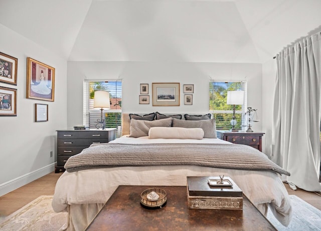 bedroom featuring multiple windows, high vaulted ceiling, and light wood-type flooring