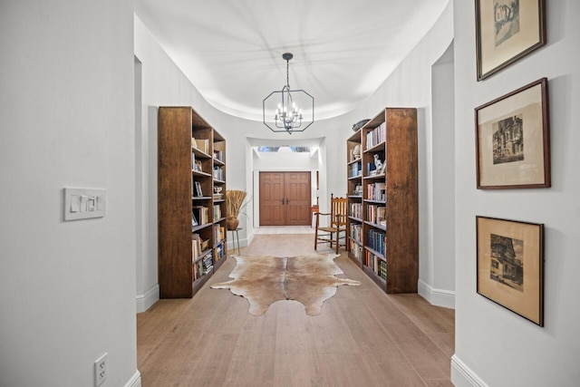 hallway with an inviting chandelier and light hardwood / wood-style floors